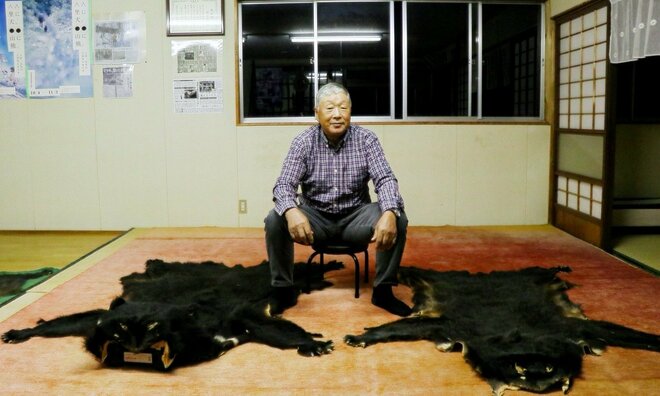 2頭のクマの毛皮を前にしたマタギの鈴木英雄