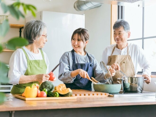 料理する高齢者夫婦と若い女性