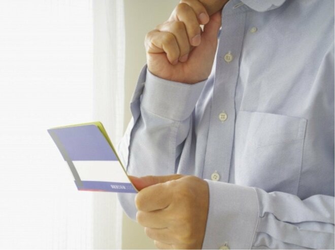 通帳を見つめる男