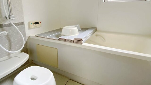 全体的に白のお風呂場、左手にシャワーと風呂椅子。画面奥にバスタブ。（写真提供／奥田明子氏）